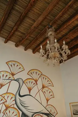 a painting of a bird on a wall with a chandelier at Beit Felfel in Esna