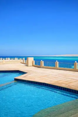 a swimming pool with the ocean in the background at Luxury Sea View Apt near Beach - 2 Pools - Balcony in Hurghada