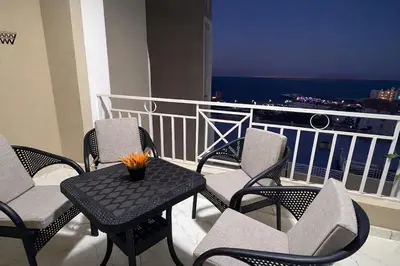 a table and chairs on a balcony with a view of the ocean at Luxury Sea View Apt near Beach - 2 Pools - Balcony in Hurghada
