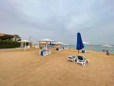 a beach with chairs and an umbrella and the ocean at Sea-Front Selena Bay Resort Apartment in Hurghada