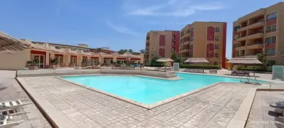 a large swimming pool in a courtyard with buildings at 2-Room Apartment with Swimming Pool in Hurghada