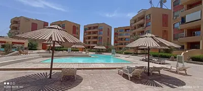 a swimming pool with chairs and umbrellas in a resort at 2-Room Apartment with Swimming Pool in Hurghada