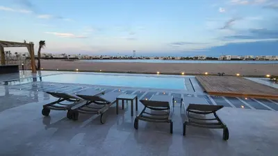 a swimming pool with chairs and a table and a view at Elgouna -4 bedroom villa with private heated pool in Hurghada