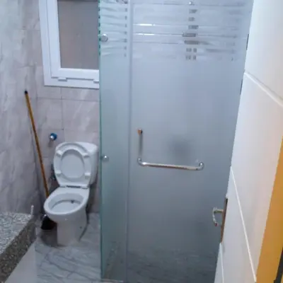 a bathroom with a toilet and a glass shower door at Amazing 1 bedroom & sofa bed at Selenabay Hurghada in Hurghada
