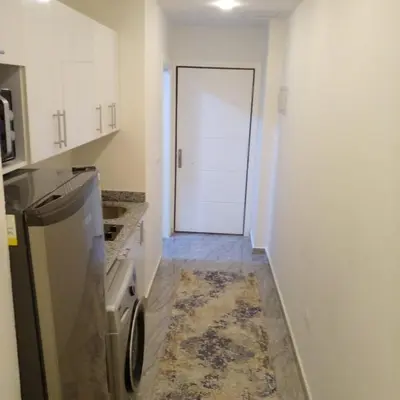 a small kitchen with a refrigerator and a door at Amazing 1 bedroom & sofa bed at Selenabay Hurghada in Hurghada