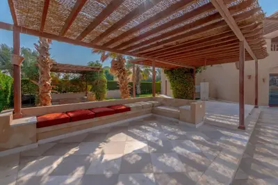 a patio with a bench and a wooden pergola at VESTA - El Gouna Residence in Hurghada