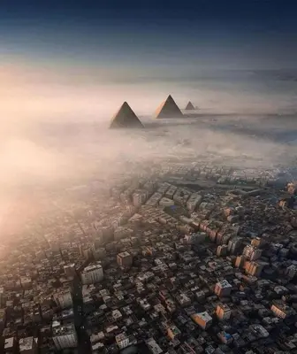 an aerial view of the pyramids of giza over a city with fog at VESTA - El Gouna Residence in Hurghada