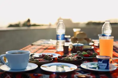 a table with cups and plates of food and drinks at Saray El Omda - Egyptian Rural Village in Luxor