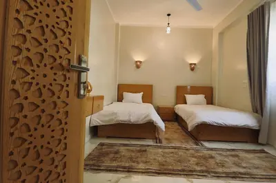 a room with two beds and a door with ajar at Luxor Hermes Guest House in Luxor