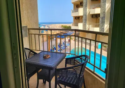 a balcony with a table and chairs and a swimming pool at La Quinta Beach Resort Hurghada in Hurghada