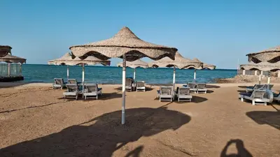 a group of chairs and umbrellas on a beach at Seaside studio with private Beach and pool in Hurghada