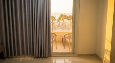 a sliding glass door with a view of a dining table at Seaside studio with private Beach and pool in Hurghada