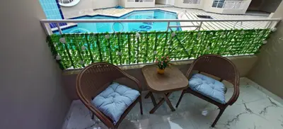 a balcony with two chairs and a table and a pool at Ramses Apartment in Hurghada