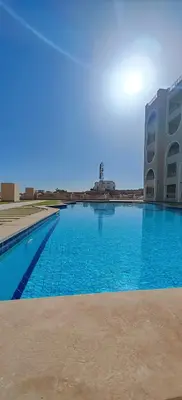 a large blue swimming pool next to a building at Ramses Apartment in Hurghada