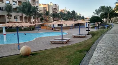 a pool with benches and umbrellas in a resort at Nobia Aqua Beach in Hurghada