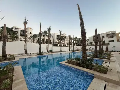 a pool at a resort with palm trees and buildings at Ancient Sands 2BR | Ground Floor, Pool Access in Hurghada