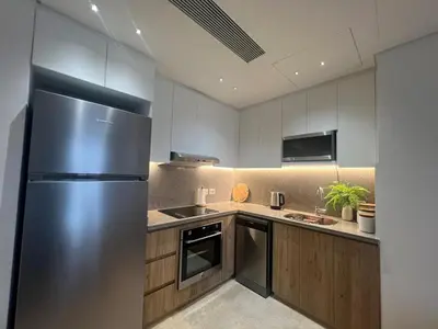 a kitchen with a stainless steel refrigerator and wooden cabinets at Ancient Sands 2BR | Ground Floor, Pool Access in Hurghada