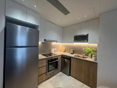 a kitchen with a stainless steel refrigerator and wooden cabinets at Ancient Sands 2BR | Ground Floor, Pool Access in Hurghada