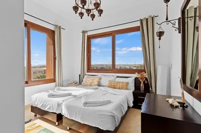 a bedroom with a large bed and two windows at South Marina Central 2BR, bathtub, Terraces & Pool in Hurghada