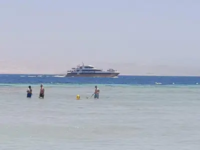 a group of people standing in the water with a boat at Tiba golden resort in Hurghada