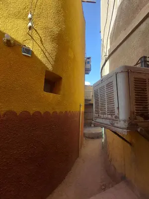 an alley with a yellow wall and an air conditioner at moon guest house in Jazīrat Aswān