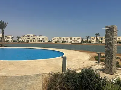 a large swimming pool in front of some houses at Colorful 1BR Apt-Free Pool & Lagoon Access In ElGouna in Hurghada