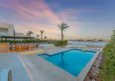 a swimming pool with tables and chairs on a house at Ancient Sands 3BR Twin Villa with a Private Patio Heated Swimming Pool & Lagoon Access in Hurghada