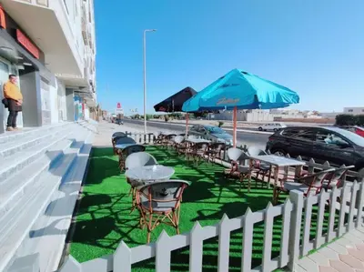 a row of tables and chairs with an umbrella on a sidewalk at Sea view studio for rent at Juliana at Hurghada in Hurghada