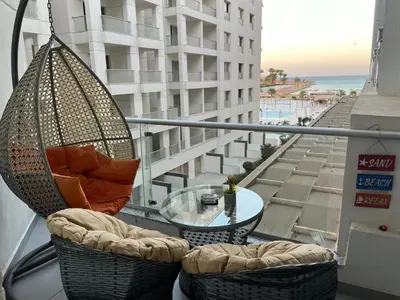 a swing chair and a glass table on a balcony at Hurghada scandic resort in Hurghada