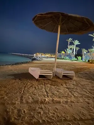 an umbrella and chairs on a beach at night at Hurghada scandic resort in Hurghada