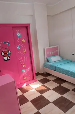 a room with two beds and a wall with a hello kitty door at المحكمة in Aswan