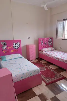two beds in a room with pink furniture at المحكمة in Aswan