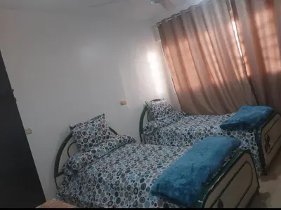 a bedroom with two beds with blue sheets and a window at شقة سكنية كبيرة in Aswan