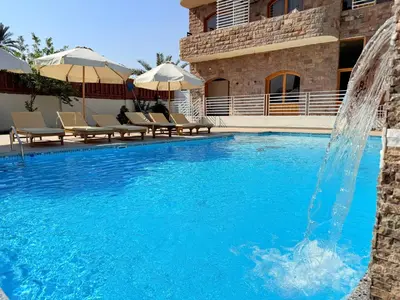 a pool with a water fountain in front of a building at Citadel Luxor in Luxor