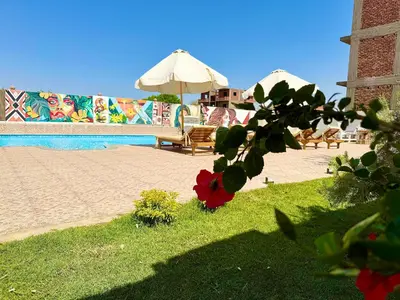 a pool with chairs and an umbrella and a red flower at Citadel Luxor in Luxor