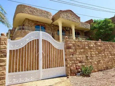 a house with a wooden gate and a stone wall at Citadel Luxor in Luxor