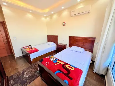 a bedroom with two beds and a room with two tables at Sun Palace House in Luxor