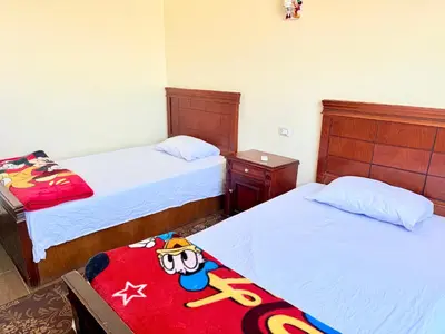 a bedroom with two beds and a toy on a blanket at Sun Palace House in Luxor