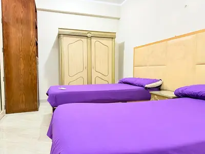 three beds in a room with purple sheets at Sun Palace House in Luxor