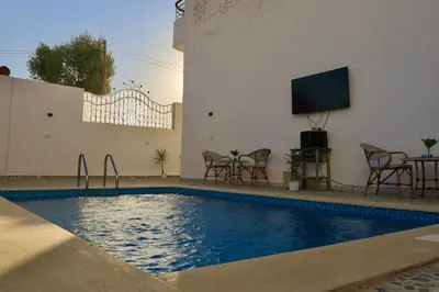a swimming pool with a tv and a table and chairs at White Gorf Hotel in Luxor