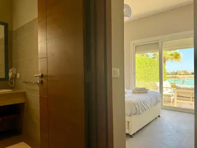 a bedroom with a bed and a view of a pool at Scenic 2BR Ground Floor - Free Pool& Lagoon Access In ElGouna in Hurghada