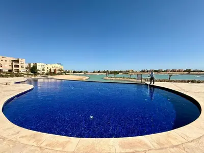 a pool of blue water with a person standing in it at Scenic 2BR Ground Floor - Free Pool& Lagoon Access In ElGouna in Hurghada