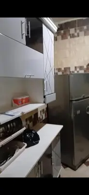 a kitchen with white counters and a black refrigerator at قصر الحجر in Aswan
