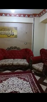 a living room with a red couch and a rug at قصر الحجر in Aswan