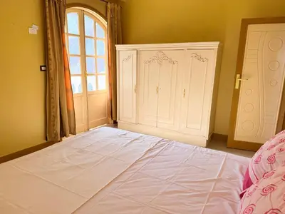 a bedroom with a large bed with a window and a door at Ramla Palace House in Luxor