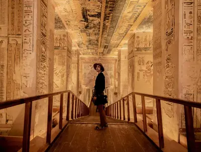 a woman standing in a hallway in an ancient room with paintings at Ramla Palace House in Luxor