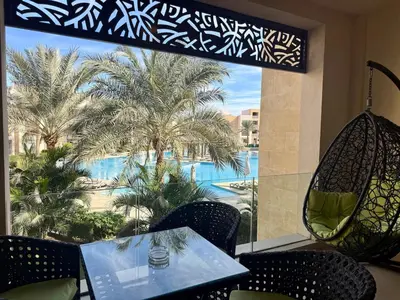 a table and chairs with a view of a pool at Cozy 2BR Plus Nanny - Free Beach&Pool In Mangroovy ElGouna in Hurghada