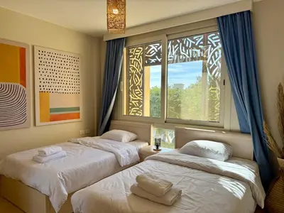 two beds in a room with two windows at Cozy 2BR Plus Nanny - Free Beach&Pool In Mangroovy ElGouna in Hurghada