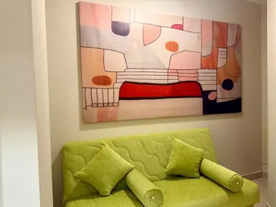 a green couch in a room with a painting at Cozy 2BR Plus Nanny - Free Beach&Pool In Mangroovy ElGouna in Hurghada