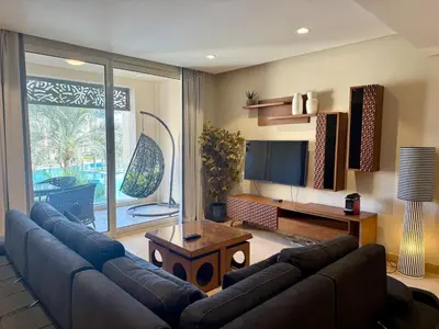 a living room with a blue couch and a television at Cozy 2BR Plus Nanny - Free Beach&Pool In Mangroovy ElGouna in Hurghada